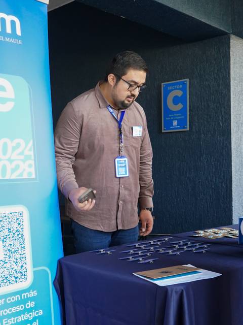 Una feria informativa en la Universidad Católica del Maule donde un expositor interactúa con una estudiante.