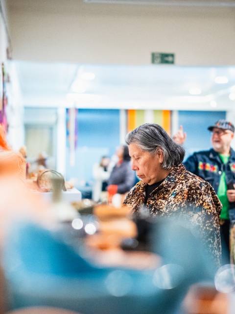 Una mujer observa obras de arte en una galería mientras otros visitantes la acompañan.