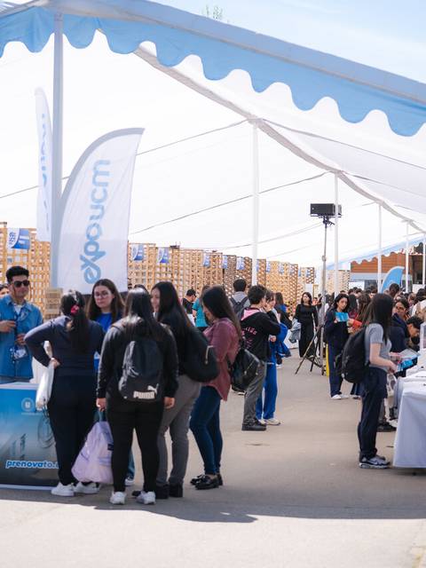 Una feria con estudiantes y stands informativos en un ambiente universitario.