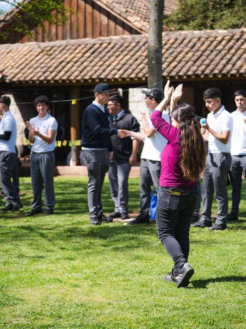 Un grupo de estudiantes aplaude mientras una compañera celebra en un entorno natural.