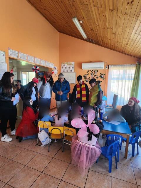 Un grupo de jóvenes celebrando una actividad en un salón decorado con globos y disfraces.