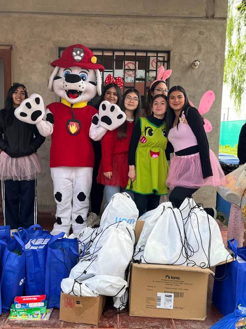Un grupo de personas disfrazadas junto a un personaje de un perro en un ambiente festivo.