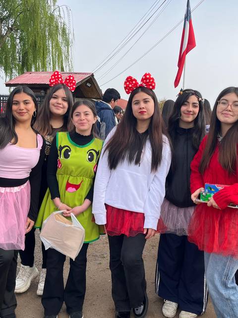 Un grupo de amigas en disfraces coloridos celebrando con alegría y risas en un evento al aire libre.