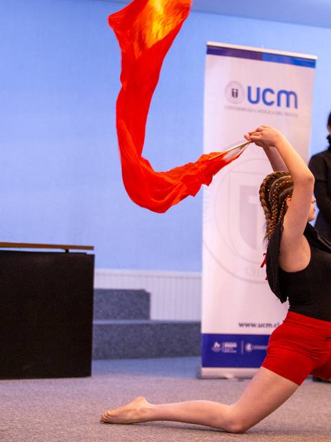 Una niña bailando con un pañuelo rojo en un evento formal.