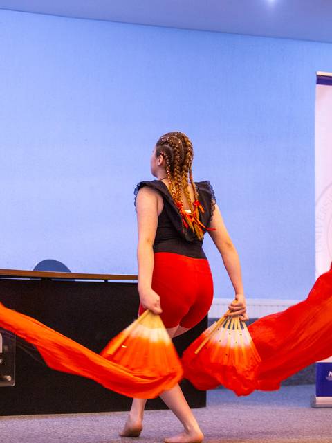 Una bailarina de fondo despliega cintas rojas en una ceremonia en la UCM.
