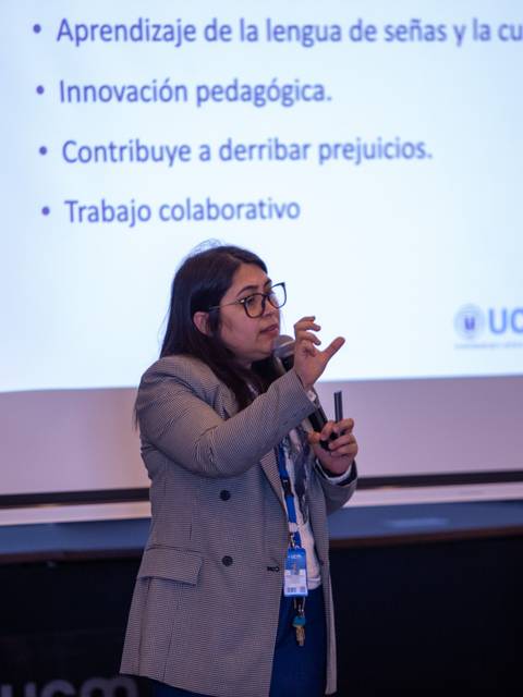 Una mujer presenta sobre el aprendizaje de la lengua de señas en un evento educativo.