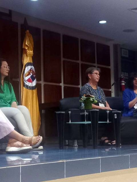 Una charla en un auditorio con varias mujeres sentadas en un panel.