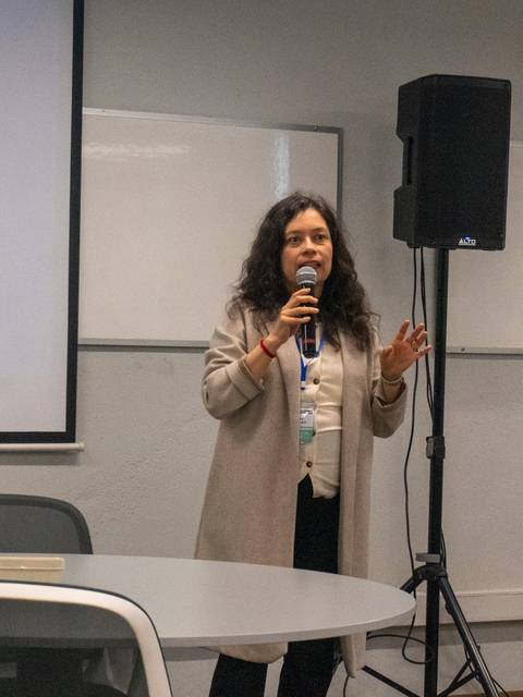 Una persona presenta en una sala de clases ante un grupo de asistentes.