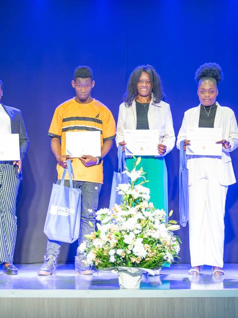 Un grupo de jóvenes sonrientes posando con diplomas en un evento de premiación.