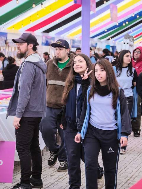 Gente caminando por una feria con sombra de colores y stands de libros.