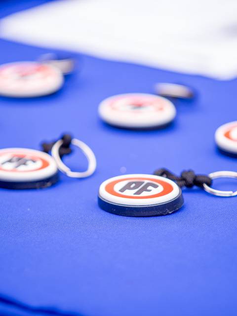 Un grupo de llaveros con el logo de PF sobre una mesa azul.