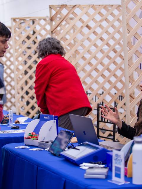 Una feria con personas interactuando en varios stands.