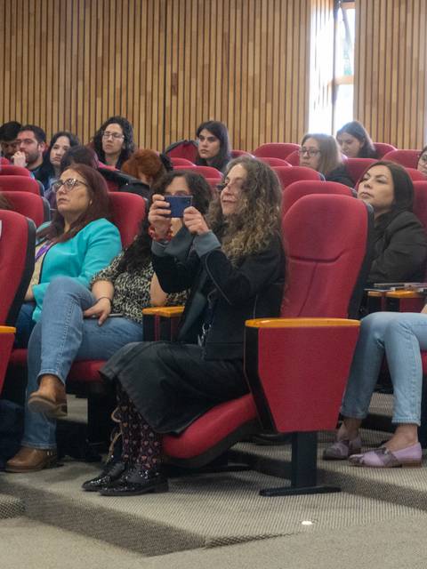 Una audiencia atenta en una sala con asientos rojos durante una presentación.