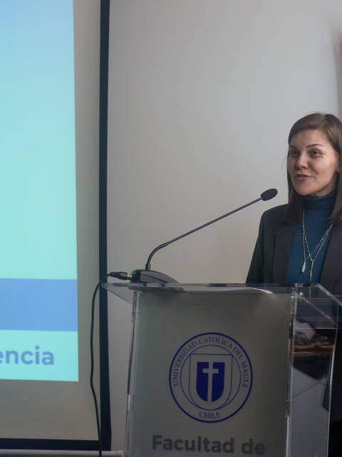Una mujer hablando en un evento académico en la universidad.