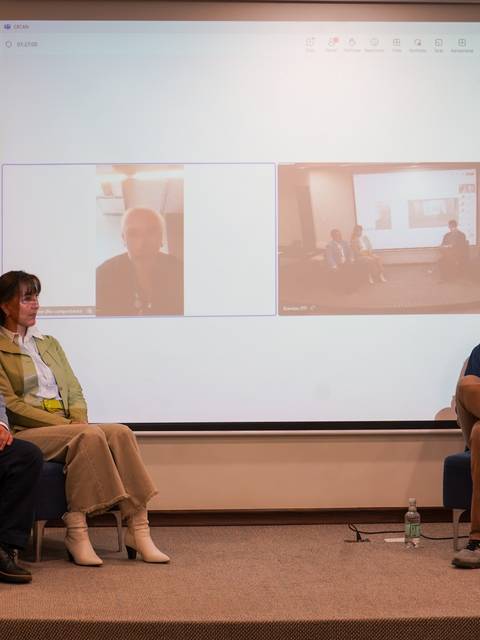 Un panel de discusión con tres participantes, dos en persona y uno en videoconferencia.