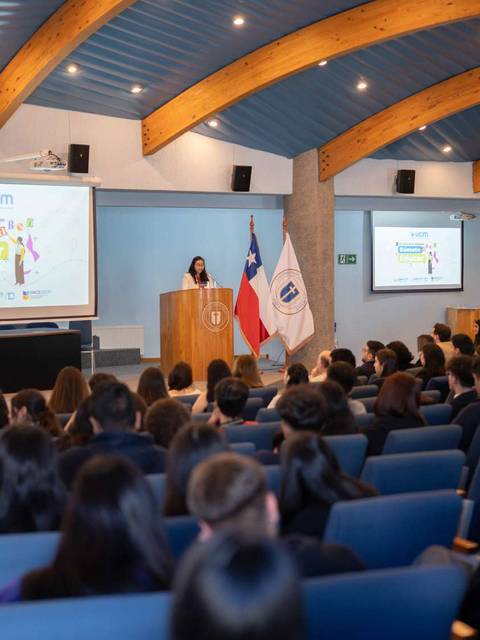 Una charla motivacional en un auditorio con muchos estudiantes atentos.