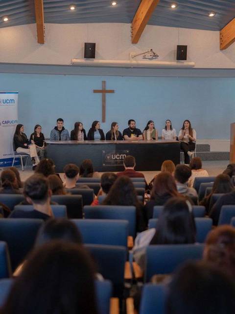 Un grupo de personas está participando en un evento académico en una sala llena.