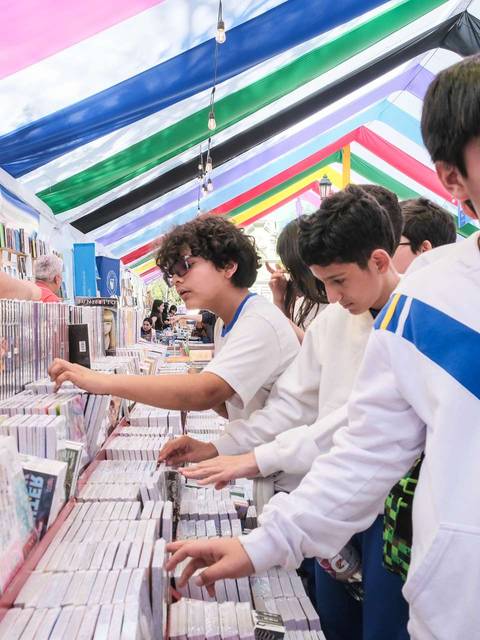 Un grupo de cabros chicos busca discos en una feria con techo de colores.