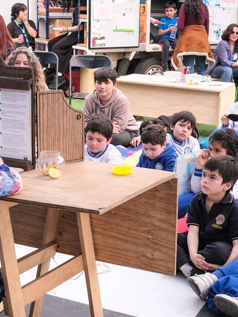 Una cuentacuentos entretiene a un grupo de niños sentados con atención.