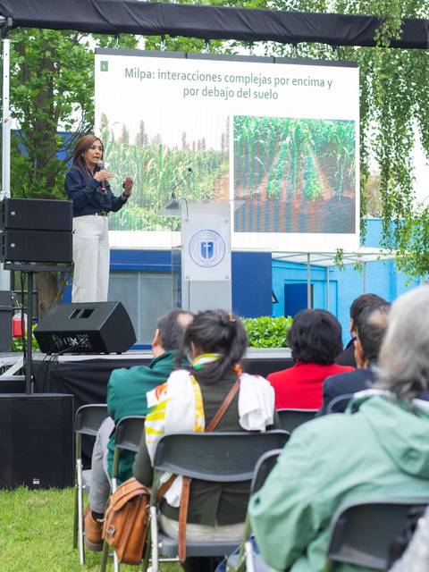 Una charla sobre agronomía al aire libre, donde una ponente interactúa con el público.