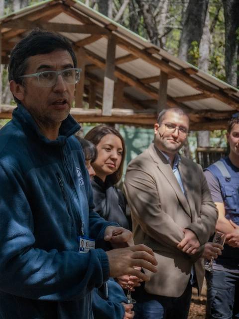 Un grupo de personas escucha atentamente a un expositor en un entorno natural.