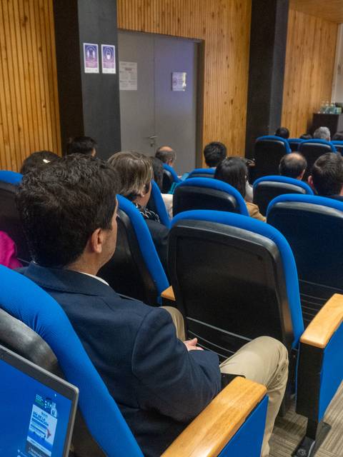 Una charla en un auditorio con asistentes atentos mirando al presentador.