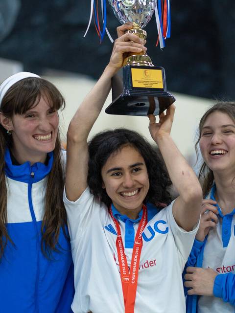 Un grupo de cinco chicas felices levantando un trofeo tras ganar un campeonato.