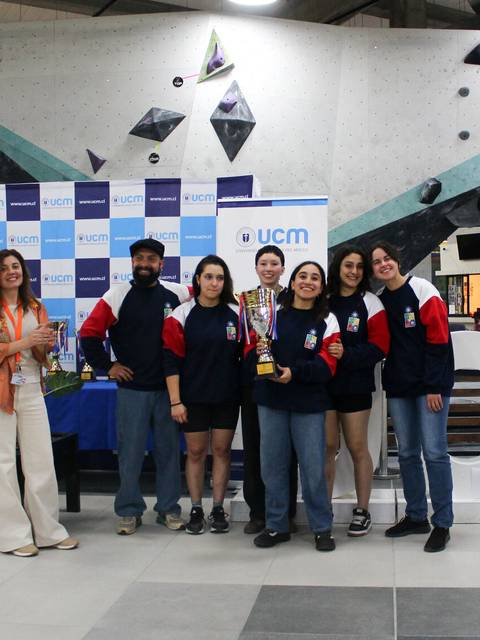Un grupo de personas celebra un triunfo en una competencia de escalada en un ambiente festivo.