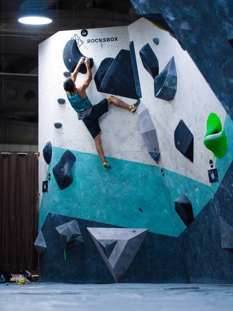 Un escalador se desafía en una pared de boulder en un gimnasio de escalada.