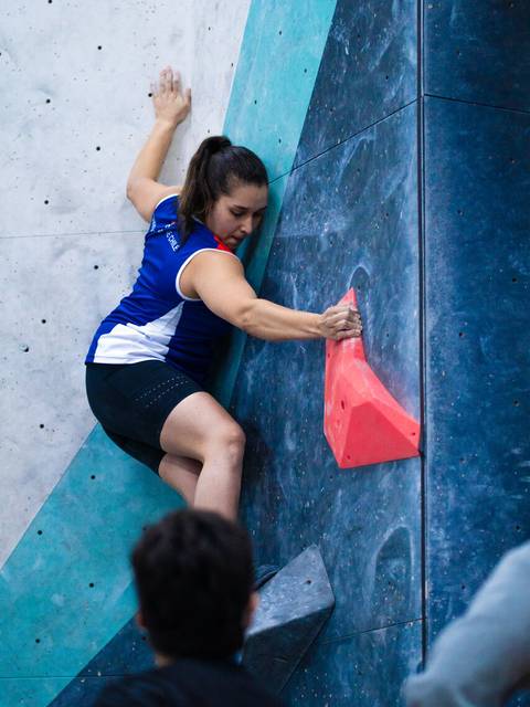 Una mujer haciendo escalada en roca en un muro de boulder.
