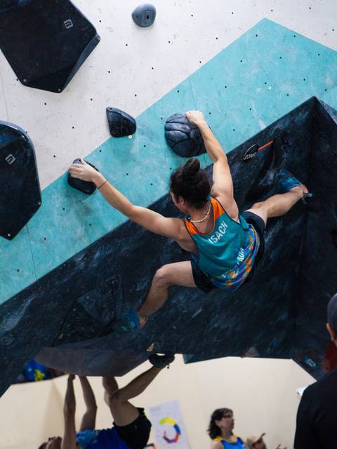 Un deportista está escalando en una pared de boulder en un gimnasio.