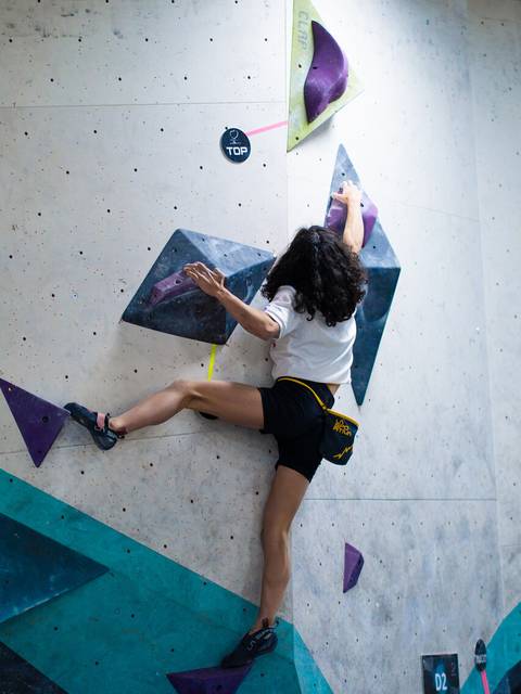 Una persona está escalando una pared de boulder en un gimnasio.