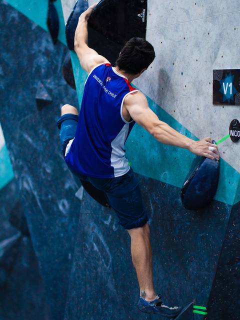 Un escalador enfrenta un bloque en una competición de escalada en roca.