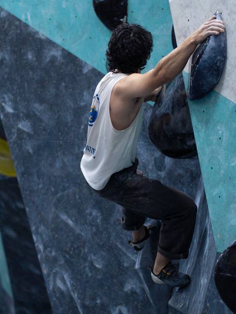 Un escalador se enfrenta a un muro de boulder en un gimnasio.