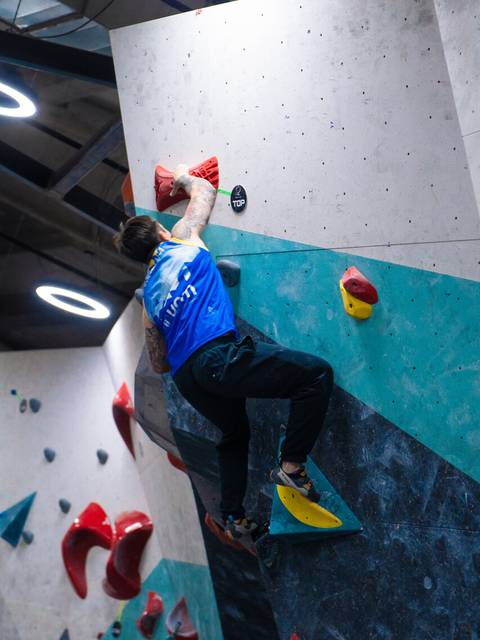 Un escalador se enfrenta a un muro de boulder en una sala de escalada.