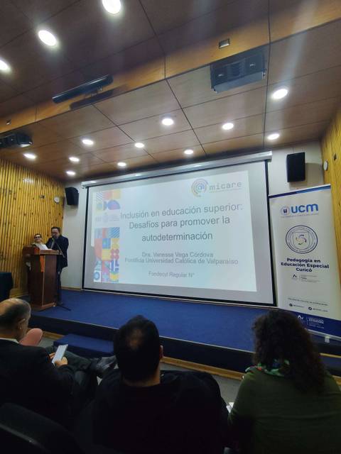 Charla sobre inclusión en educación superior en una sala con proyector y público atento.