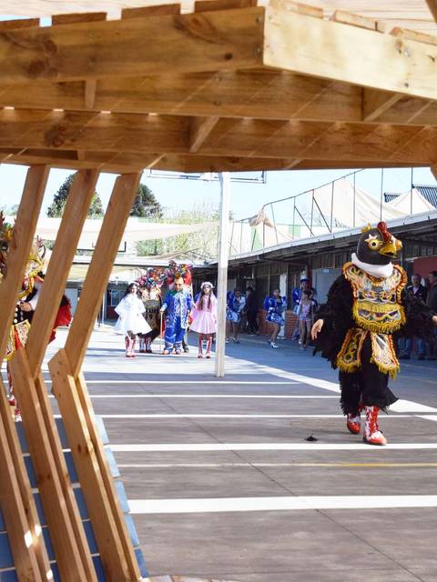 Una celebración donde grupos de personas desfilan con trajes coloridos en un ambiente festivo.