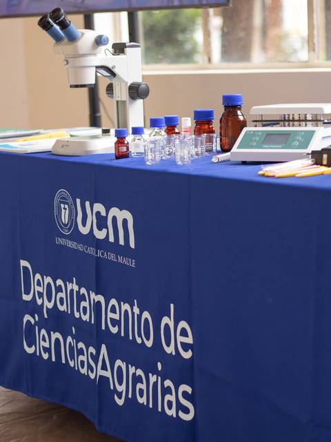Mesa de exhibición del Departamento de Ciencias Agrarias de la UCM con equipamiento y materiales de laboratorio.