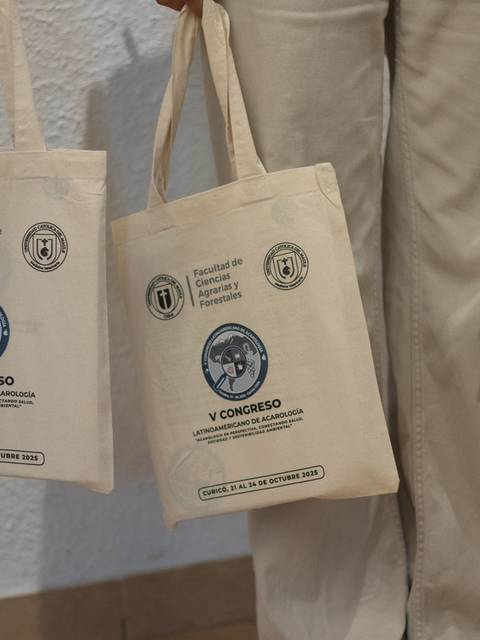 Personas sosteniendo bolsitas de tela con motivos del congreso.