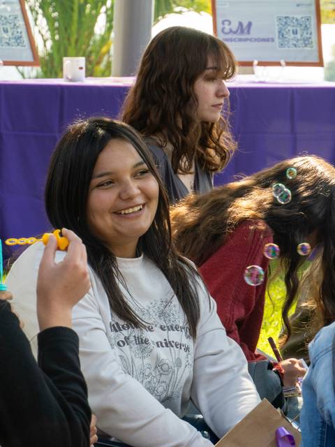 Un grupo de jóvenes se divierte al aire libre, con risas y burbujas de jabón.