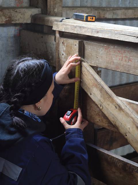 Una persona está midiendo una estructura de madera en un recinto.