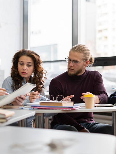 Cuatro personas discutiendo un tema en un ambiente académico y colaborativo.
