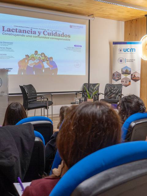 Una presentación sobre lactancia y cuidados en un auditorio con público atento.