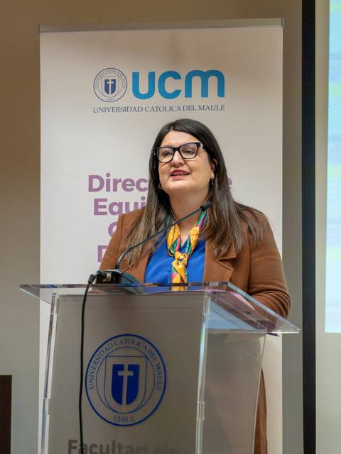 En una charla en la Universidad Católica del Maule, una mujer habla con confianza frente a un público.