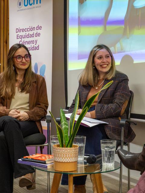 En un panel de discusión, dos mujeres conversan sobre temas de equidad de género en un ambiente académico.