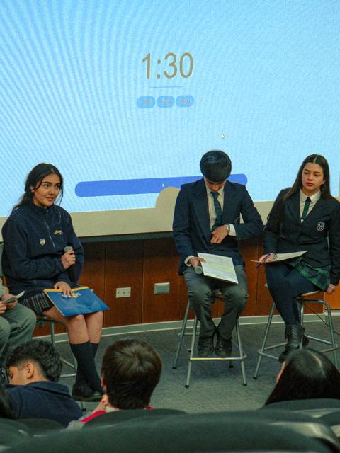 Un grupo de estudiantes discutiendo en un panel en un auditorio.