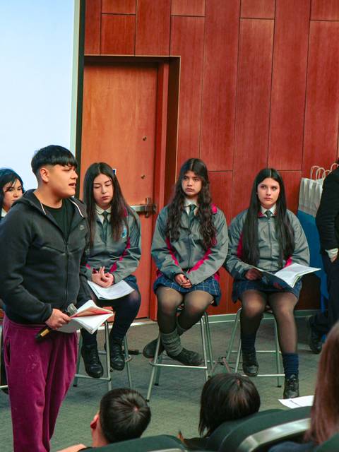 Un grupo de estudiantes presenta un proyecto frente a sus compañeros en un auditorio.