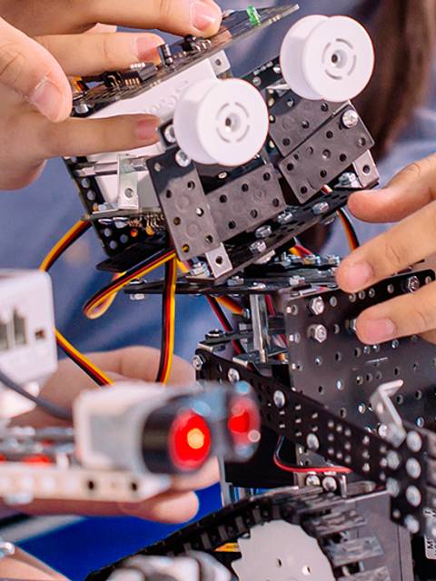 Un grupo de personas trabaja en la construcción de un robot utilizando piezas y componentes electrónicos.