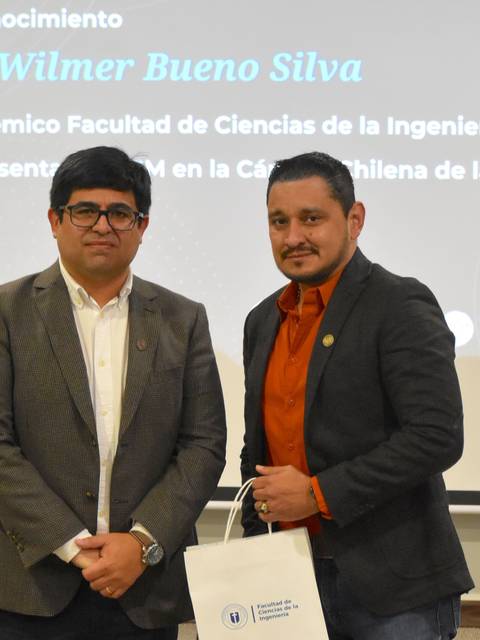 Dos hombres posando juntos en un evento de reconocimiento en Chile.