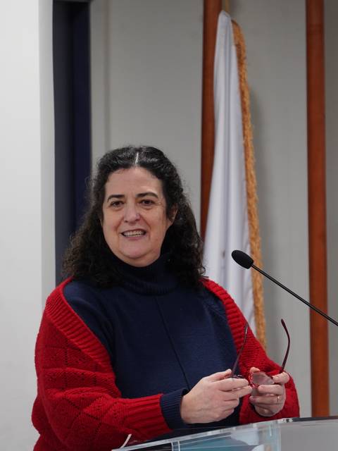 Una mujer sonriente está dando una charla en un podio.